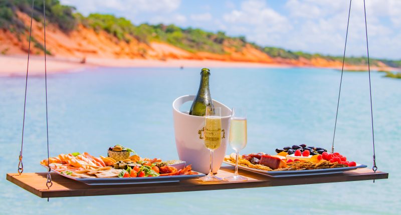 Floating platter board and champagne infront of cliffs